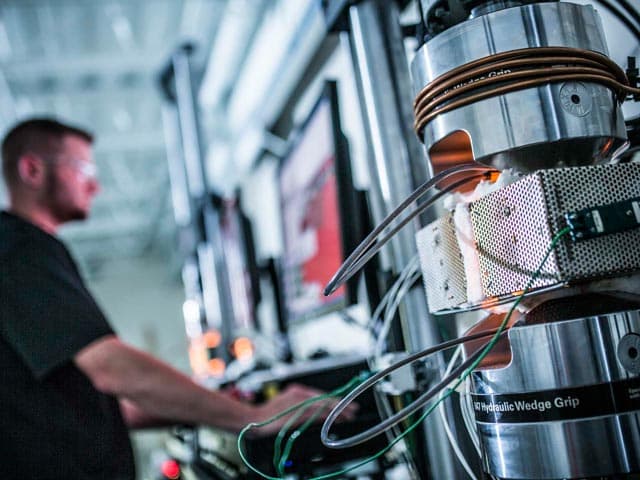 Element materials testing specialist examining sample with protective equipment for quality analysis