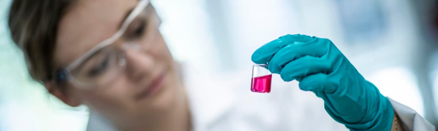 Element water testing scientist studying pink liquid in a vial