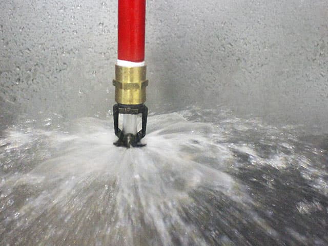 Element fire and flammability testing engineer standing in front of test frame glowing from high-temperature fire testing