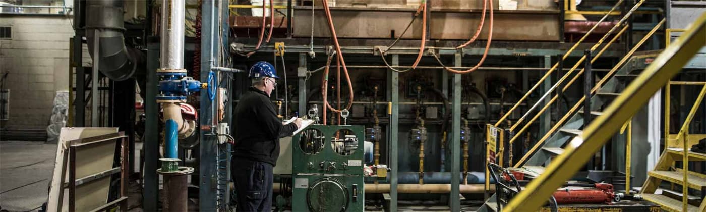 Testing engineer checking clipboard in front of testing equipment