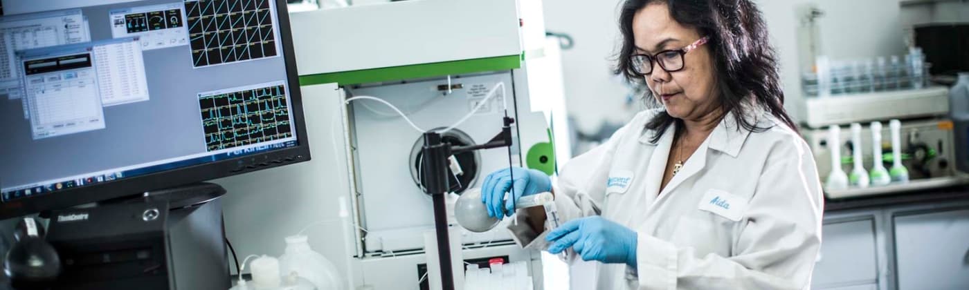 Element chemist pouring chemicals from beaker into a vial in test lab