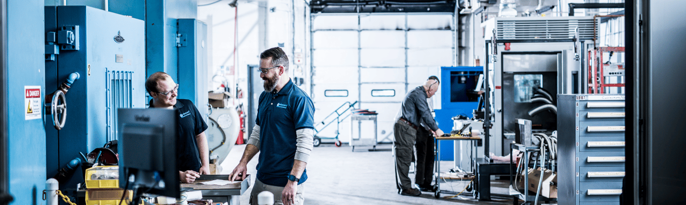 Two testing engineers chatting in Element product  testing laboratory with environmental simulation testing chambers in background