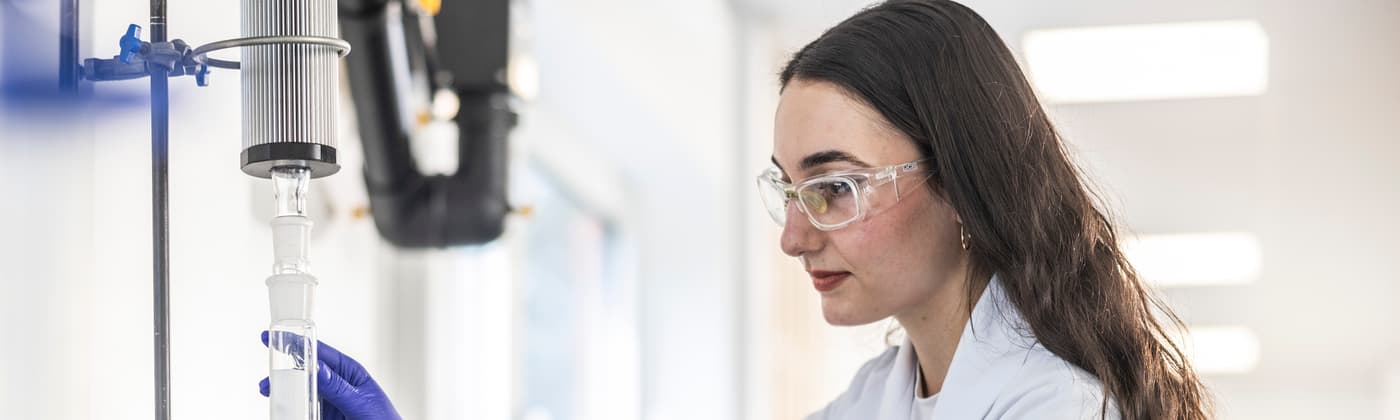 Element  scientist in white coat and safety goggles in life sciences testing laboratory interacting with advanced analytical equipment for pharmaceutical research