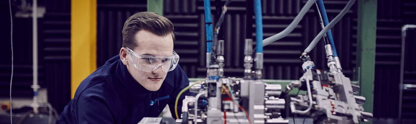 Product qualification testing engineer looking at an engine being tested on a shaker table in a product qualification testing lab