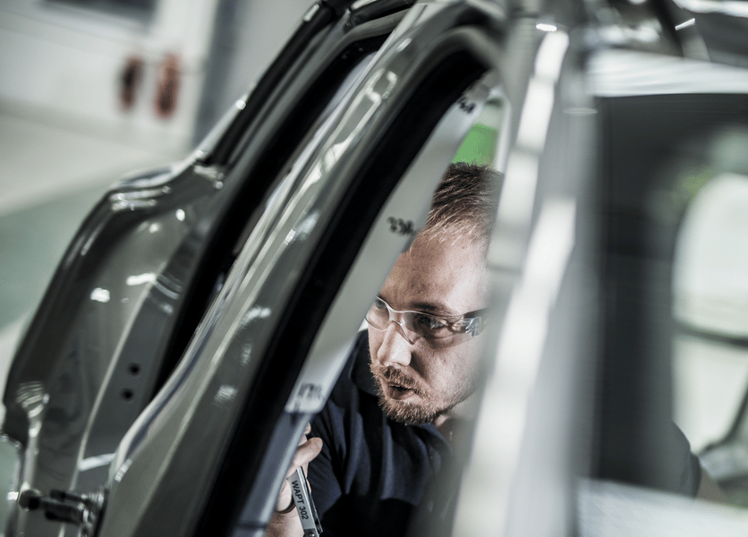 Testing engineer in a vehicle studying the window and trim in a testing laboratory