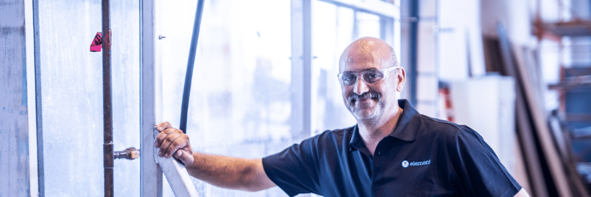 Element building products testing engineer in front of glass panel in industrial facility