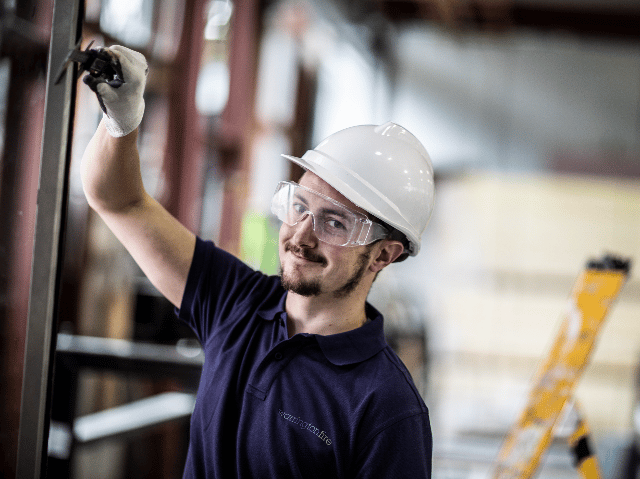 Element structural testing engineer with safety equipment conducting building materials inspection